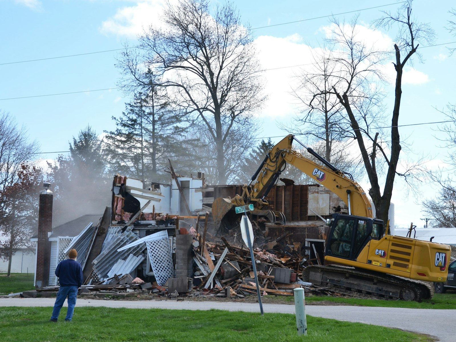 A house is being demolished by a backhoe