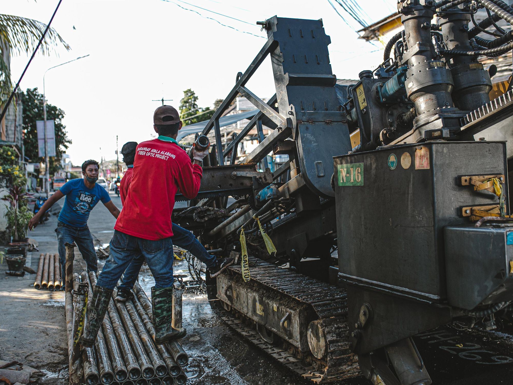 Urban scene of construction workers operating heavy machinery for street drilling.