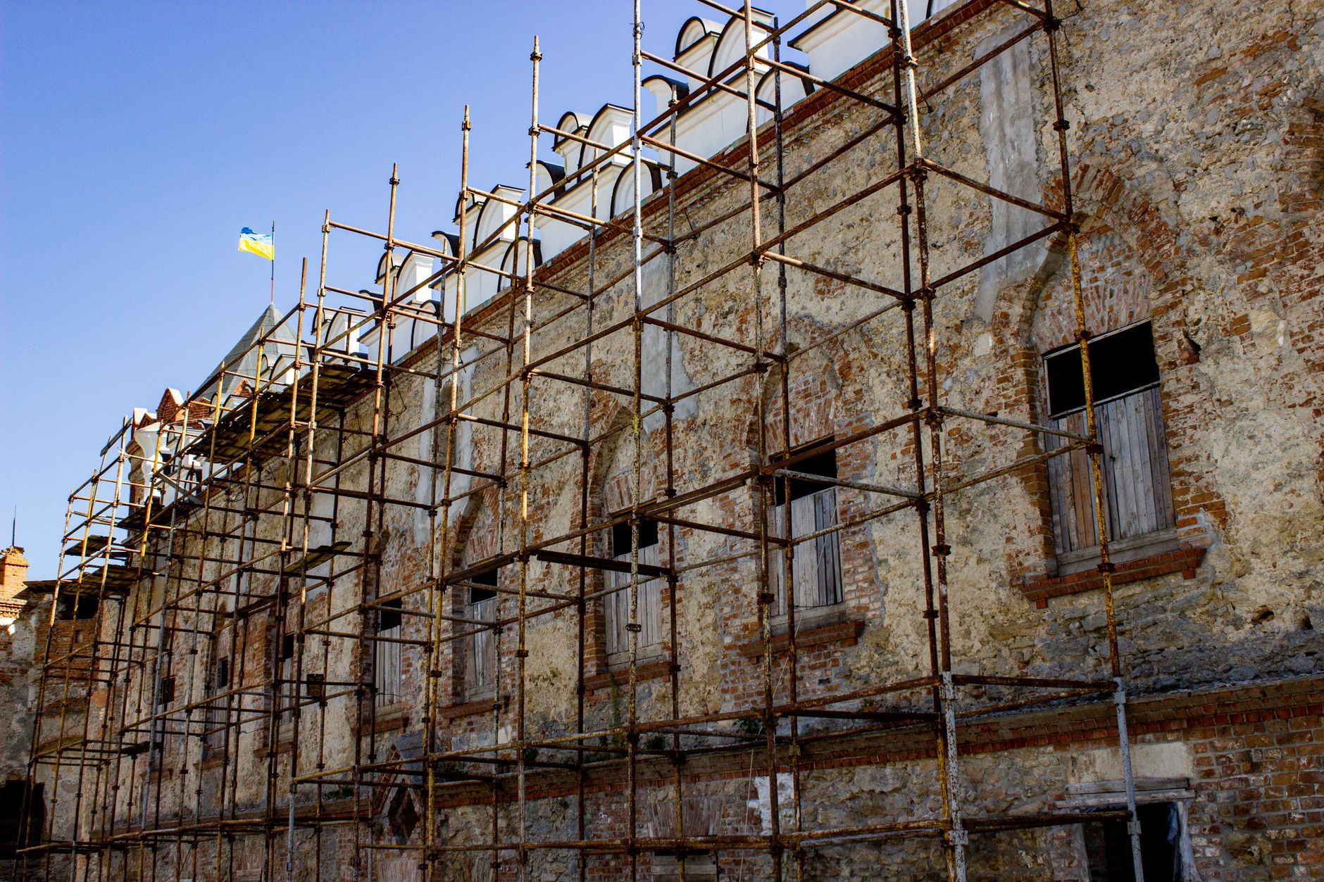 Scaffolding set up on an old brick building under restoration, with a flag above.