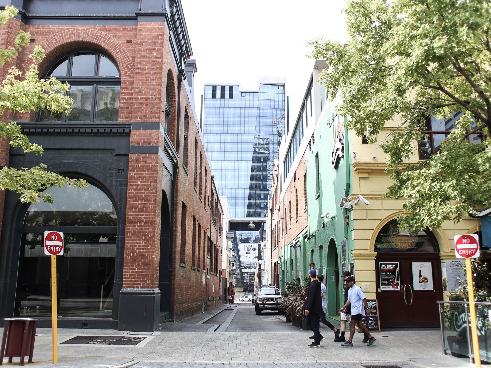 People walking in urban street with mix of historic and modern buildings.